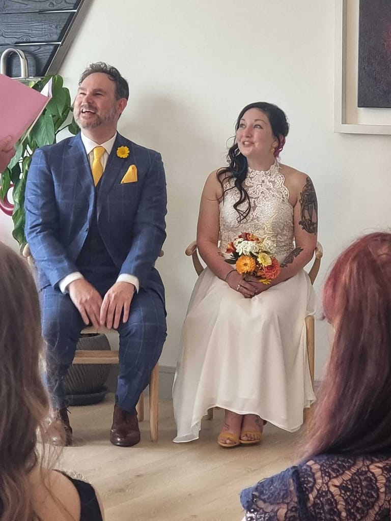 Bride and groom seated at Dunmore House Hotel during their wedding ceremony, smiling with joy.